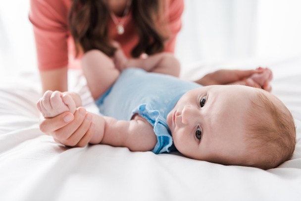 ベッドの上で幼児の娘の手に触れる女性の  - 写真・画像