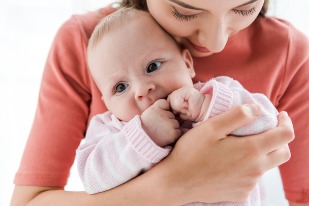 mãe segurando em braços adorável bebê filha em casa
  - Foto, Imagem