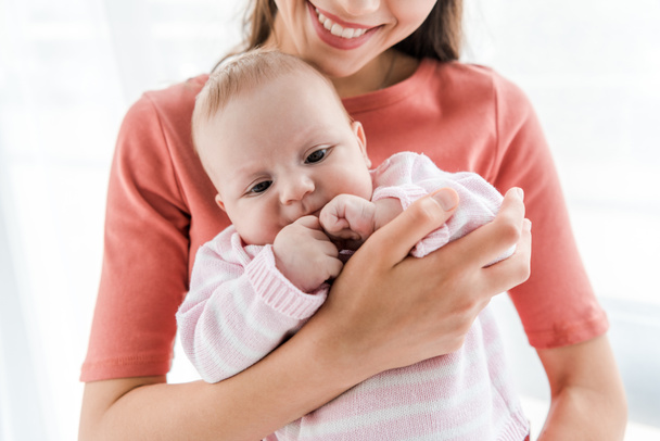 cropped view of cheerful mother holding in arms adorable infant daughter at home  - Fotografie, Obrázek