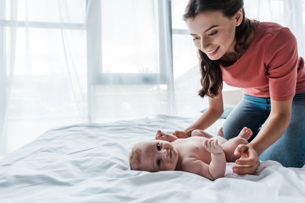 happy mother looking at infant daughter lying on bed  - Photo, Image