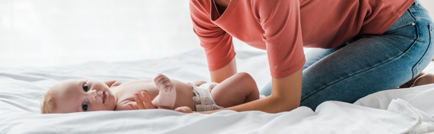 colpo panoramico di madre toccando bambino bambino carino sdraiato sul letto
  - Foto, immagini
