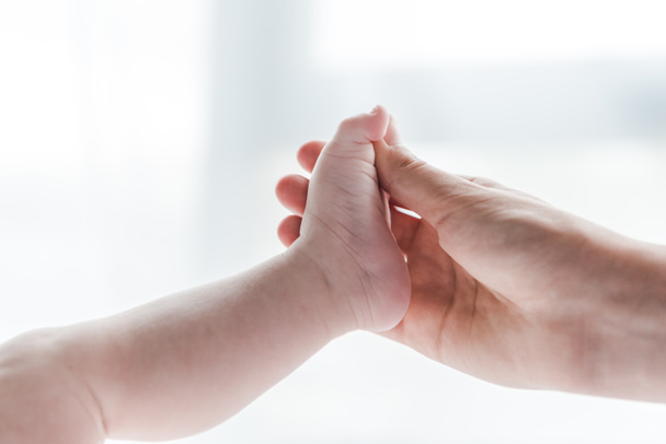cropped view of woman doing massage while touching leg of infant baby  - Foto, Imagen