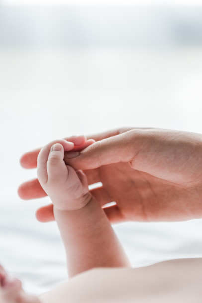 cropped view of woman doing massage while touching hand of infant baby  - Fotoğraf, Görsel