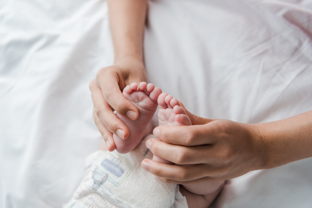 вид сверху на маму, делающую массаж во время прикосновения к ногам младенца
  - Фото, изображение