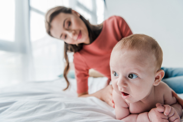 selective focus cute infant baby near happy mother in bedroom  - Foto, Imagem