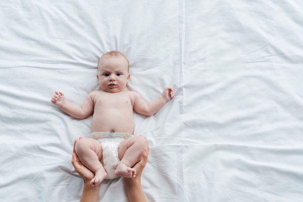 kivágott kilátás anya megható lábak imádnivaló baba lánya pelenkában  - Fotó, kép