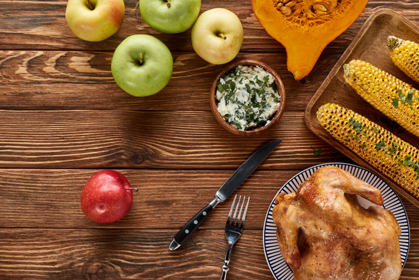 Elmaların üst görüntüsü, kızarmış hindi, balkabağı ve ahşap masada servis edilen ızgara mısır. - Fotoğraf, Görsel