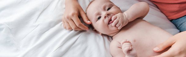 plan panoramique de mère attentionnée touchant bébé mignon sur le lit
  - Photo, image
