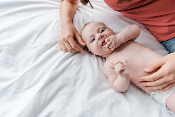 ベッドの上で可愛い赤ちゃんに触れる思いやりのある女性の  - 写真・画像