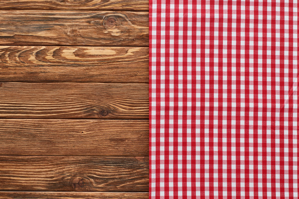bovenaanzicht van rode geruite servet op houten tafel - Foto, afbeelding