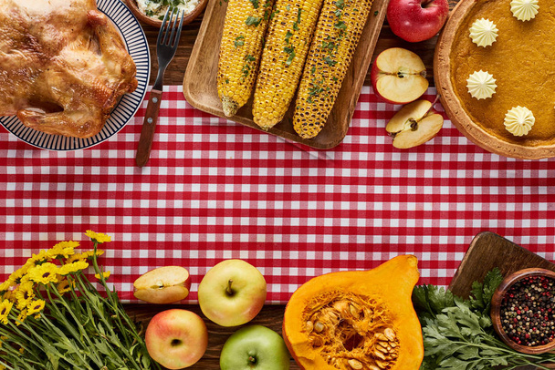 vista superior de pavo asado, pastel de calabaza y verduras a la parrilla servidas en mesa de madera con servilleta a cuadros roja
 - Foto, imagen