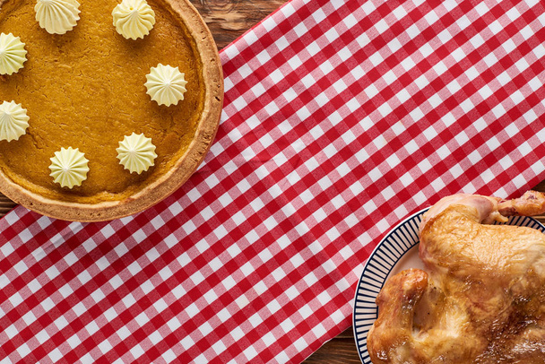 top view of delicious pumpkin pie and roasted turkey served on rustic plaid napkin on wooden table - Fotoğraf, Görsel