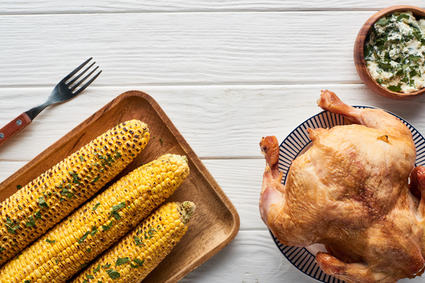 top view of roasted turkey, apples and grilled corn served on white wooden table - Foto, afbeelding