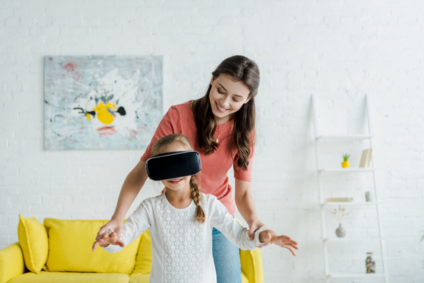 happy babysitter looking at cute kid in virtual reality headset  - Фото, зображення