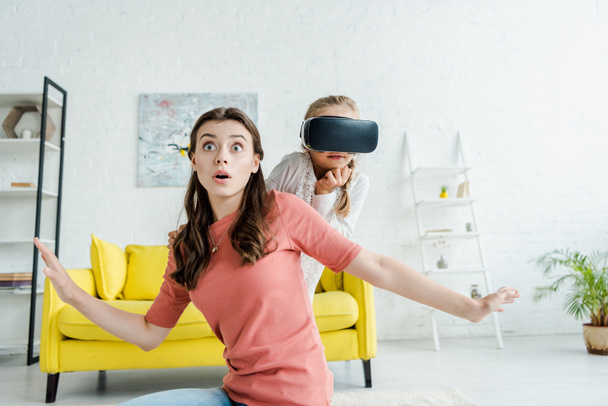 здивована няня з простягнутими руками біля дитини в гарнітурі віртуальної реальності
  - Фото, зображення