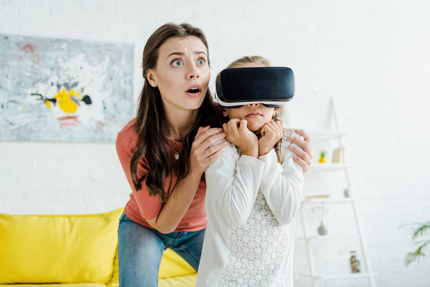 shocked babysitter standing near scared child in virtual reality headset  - Photo, Image