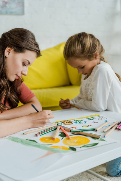 selective focus of babysitter drawing near cute kid in living room  - Фото, зображення