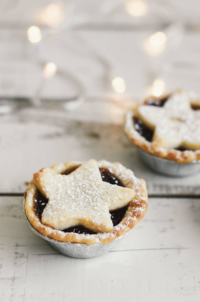 Mince pie served on wooden table, Christmas lights on background. Typical winter dessert - Photo, Image