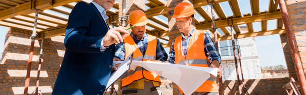 panoramic shot of businessman near builders holding blueprint - Photo, Image