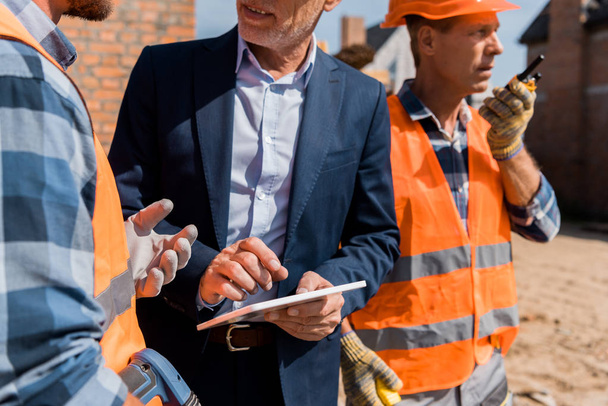cropped view of constructor gesturing near coworker and businessman with digital tablet  - Photo, Image