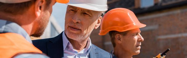 panoramic shot of constructor near businessman and coworker  - Foto, immagini