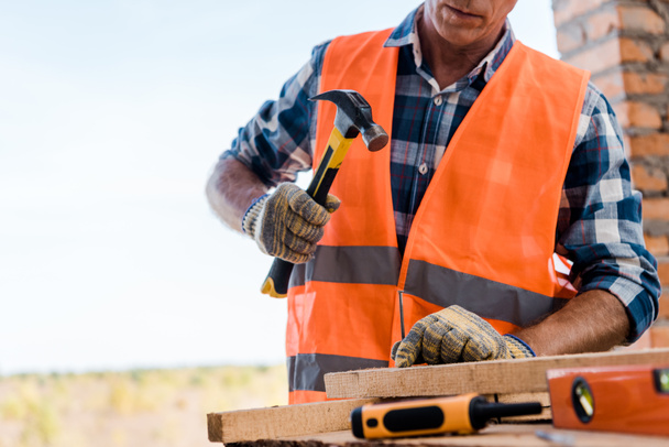 cropped view of middle aged constructor holding hammer  - Photo, Image