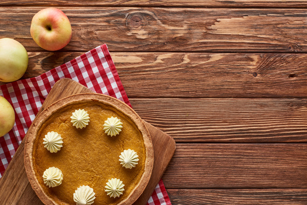 top view of pumpkin pie and apples served at wooden table with plaid napkin for Thanksgiving dinner - Φωτογραφία, εικόνα