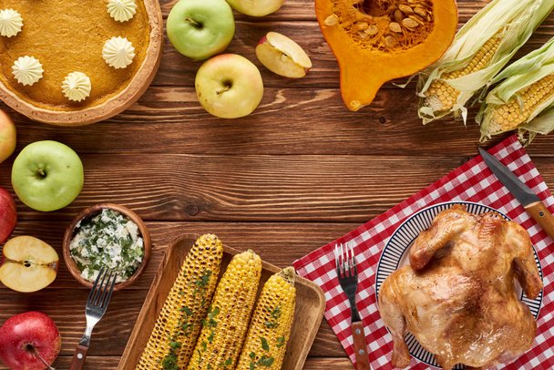 сверху вид тыквенного пирога, индейки и овощей подается за деревянным столом на ужин в честь Дня благодарения
 - Фото, изображение