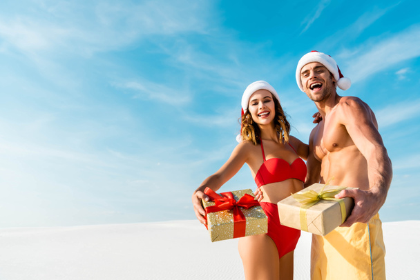 sexy and smiling girlfriend and boyfriend holding gifts on beach in Maldives  - Foto, Imagen