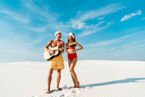 sexy girlfriend and boyfriend playing acoustic guitar on beach in Maldives  - Foto, imagen
