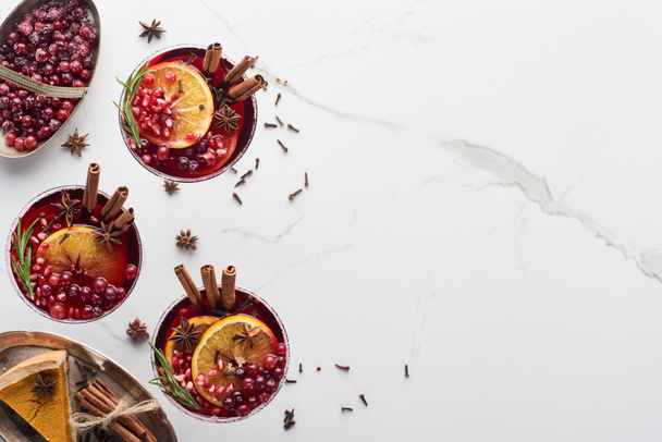 top view of christmas cocktails with orange, pomegranate, cinnamon, frozen  cranberry and pie - Foto, afbeelding