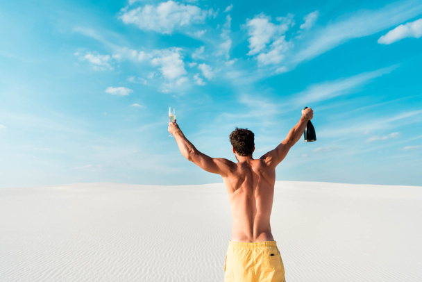 back view of sexy man holding glass and bottle on beach in Maldives  - Photo, Image