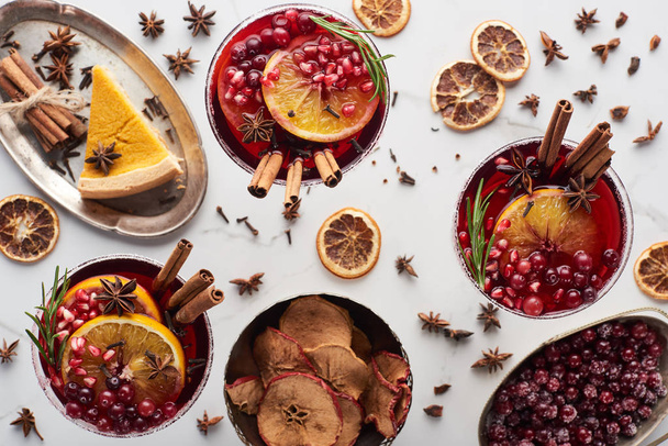 top view of christmas cocktails with orange, pomegranate, cinnamon, pie on tray, dry apples and frozen cranberry  - Фото, зображення