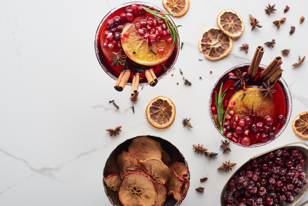 top view of christmas cocktails with orange, pomegranate, cinnamon, dry apples and frozen cranberry  - Zdjęcie, obraz