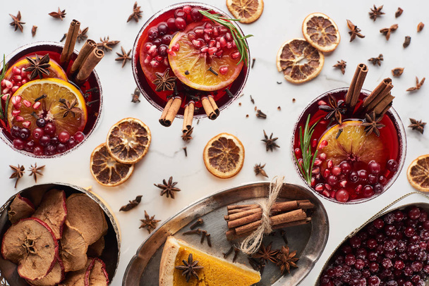 top view of christmas cocktails with orange, pomegranate, cinnamon, pie on tray, dry apples and frozen cranberry  - Foto, imagen