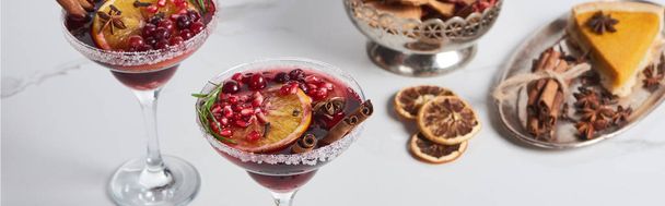 panoramic shot of christmas cocktail with orange, pomegranate, cinnamon and apple pie  - 写真・画像