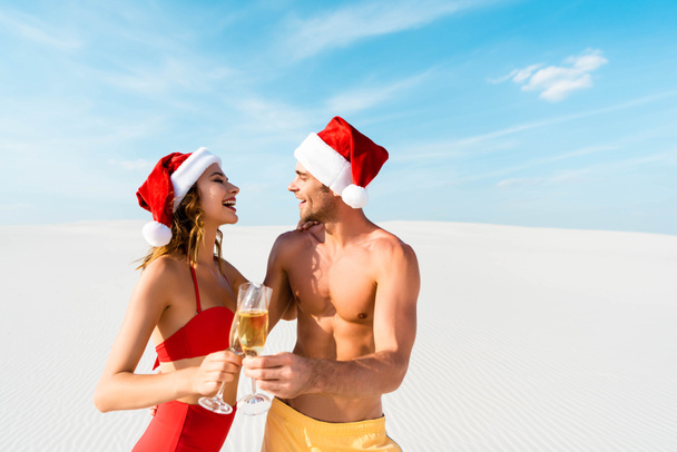 Seksi kız arkadaş ve erkek arkadaş şampanya bardaklarıyla şıngırdıyor ve Maldivler 'de kumsalda sarılıyorlar.  - Fotoğraf, Görsel