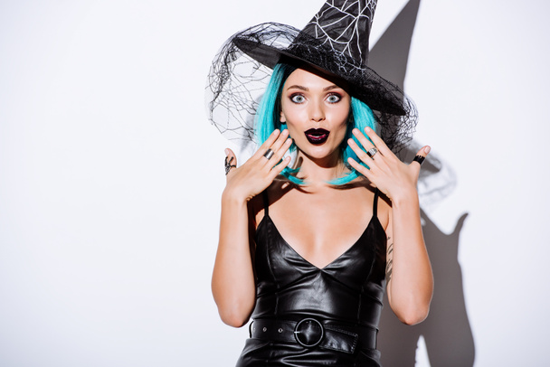 shocked girl in black witch Halloween costume with blue hair on white background - Photo, image