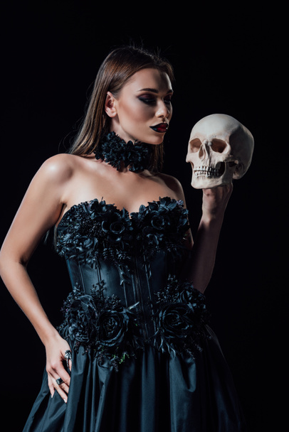 scary vampire girl in black gothic dress holding human skull isolated on black - Photo, Image