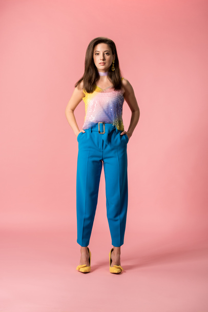 full length view of young stylish disco girl with hands in pockets isolated on pink - Fotó, kép