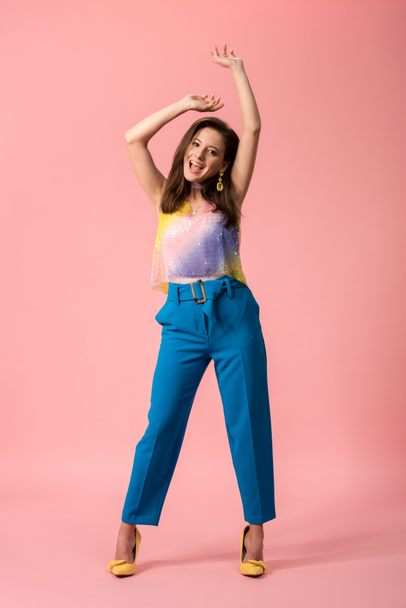 full length view of happy young stylish disco girl dancing on pink - Photo, Image