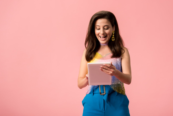 excited young stylish disco girl holding digital tablet isolated on pink - Φωτογραφία, εικόνα