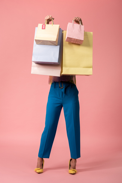 full length view of stylish disco girl holding shopping bags in front of face on pink - Foto, immagini