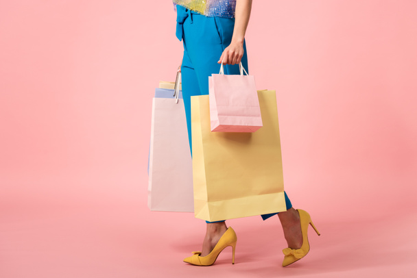 cropped view of stylish disco girl walking with shopping bags on pink - Valokuva, kuva