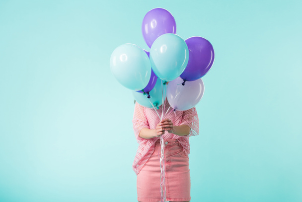 chica en traje rosa sosteniendo globos en frente de la cara aislado en turquesa
 - Foto, Imagen