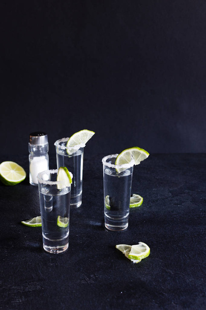 Shot glasses of gold tequila with a rim of salt, and lime slices. - Fotoğraf, Görsel