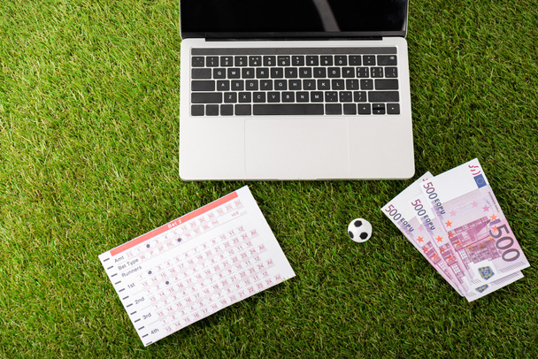 játék foci labda és fogadási lista közelében laptop zöld füvön, sport fogadási koncepció - Fotó, kép