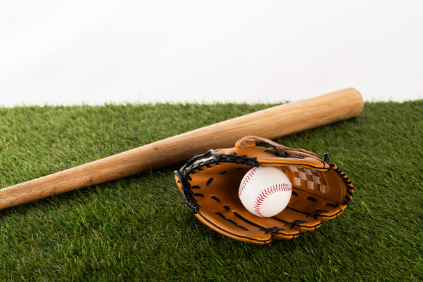 Beyazlara izole edilmiş yeşil çimlerde beyzbol sopası, eldiven ve top, spor bahisleri konsepti - Fotoğraf, Görsel