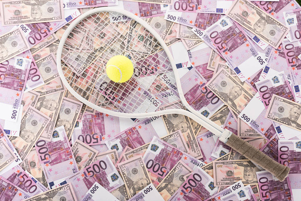 górny widok rakiety tenisowej i piłki na banknotach euro i dolara, koncepcja zakładów sportowych - Zdjęcie, obraz