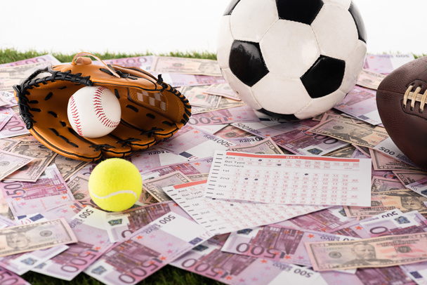 baseball kesztyű és labda, foci, tenisz és rögbi labdák közelében fogadási listák euró és dollár bankjegyek elszigetelt fehér, sportfogadási koncepció - Fotó, kép